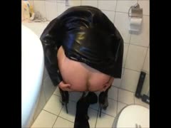 Black-clad scat homosexual urinating on the floor of a restroom